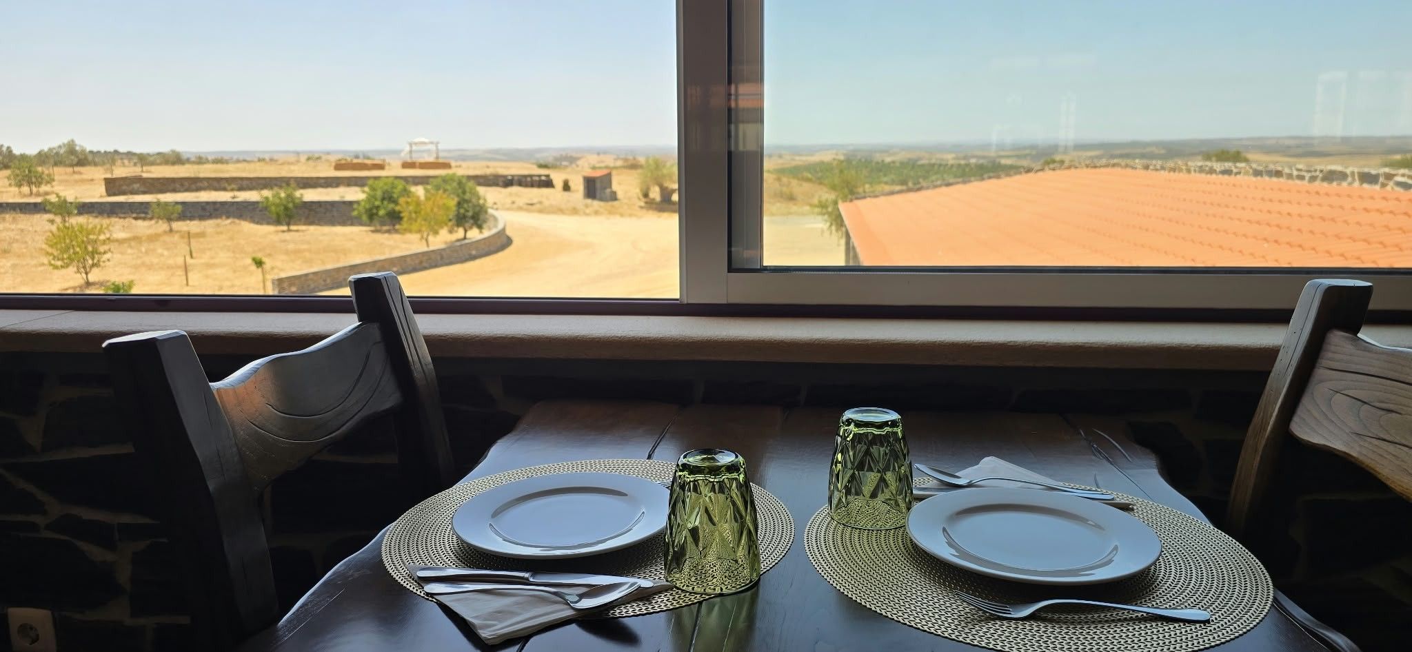 Ein Tisch für zwei Personen mit Blick auf eine ländliche Landschaft durch ein Fenster.