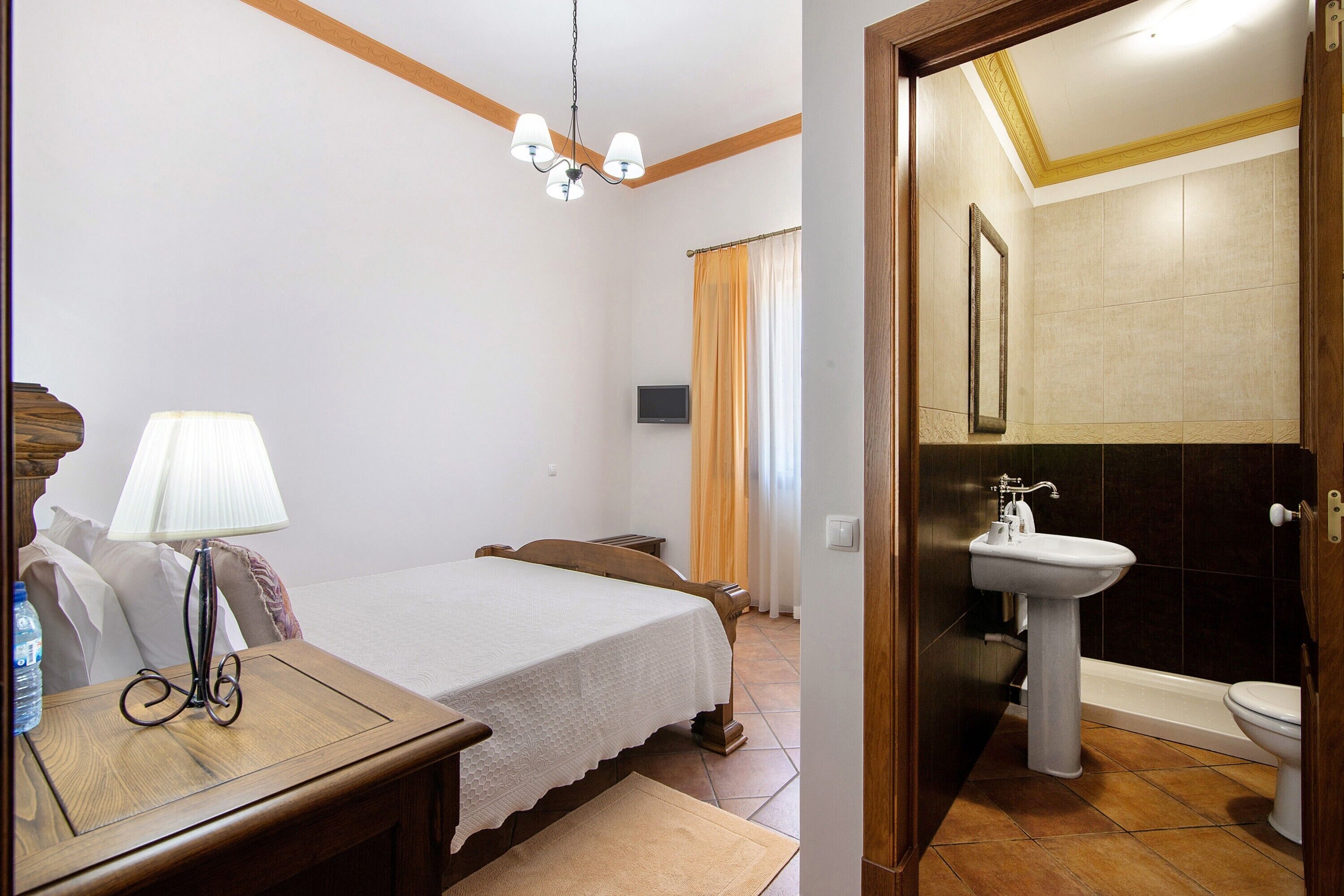 Une chambre à coucher avec un lit, une table de chevet, une lampe et un téléviseur fixé au mur.