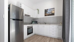 Eine moderne Küche mit weißen Schränken, Edelstahlgeräten und einer gefliesten Spritzschutzwand.
