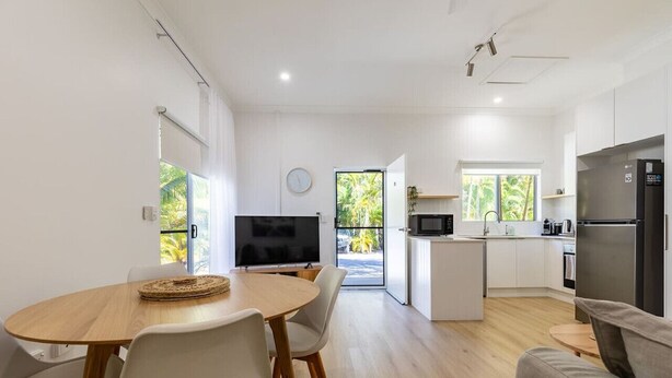 Eine moderne Küche mit Essbereich, Fernseher und Blick ins Freie.
