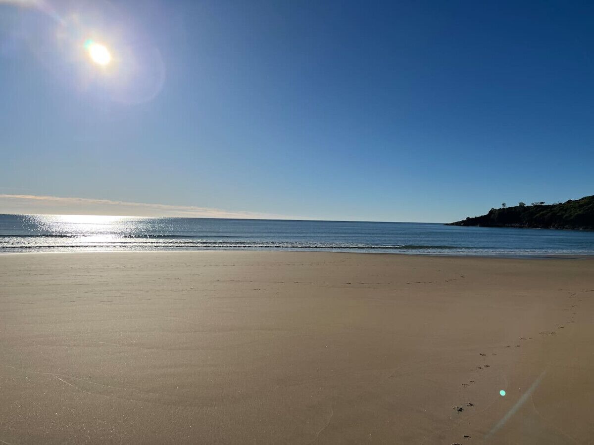 A beach with a clear sky and calm sea.