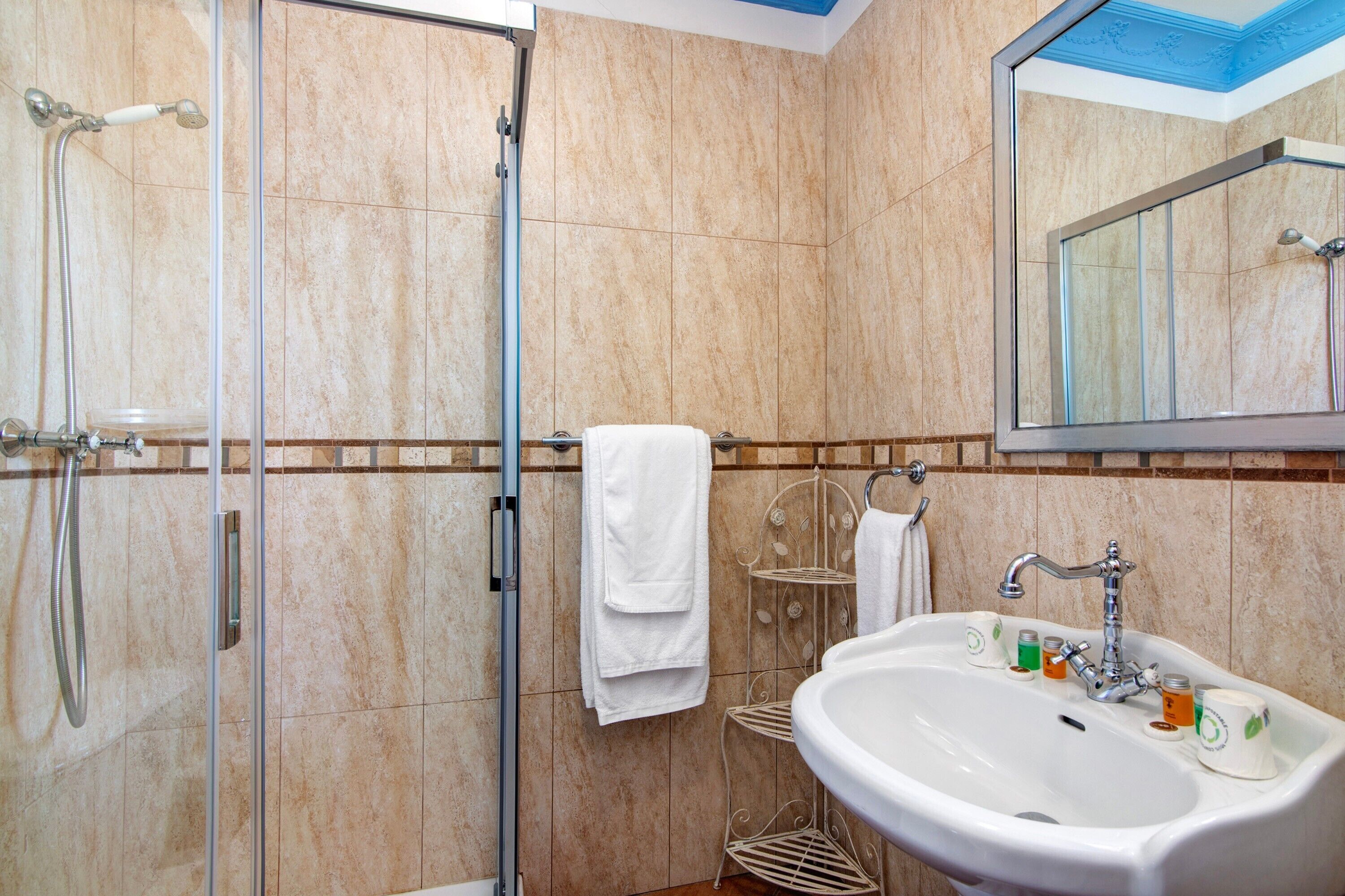 Un baño con cabina de ducha de vidrio, lavabo con artículos de aseo y espejo.