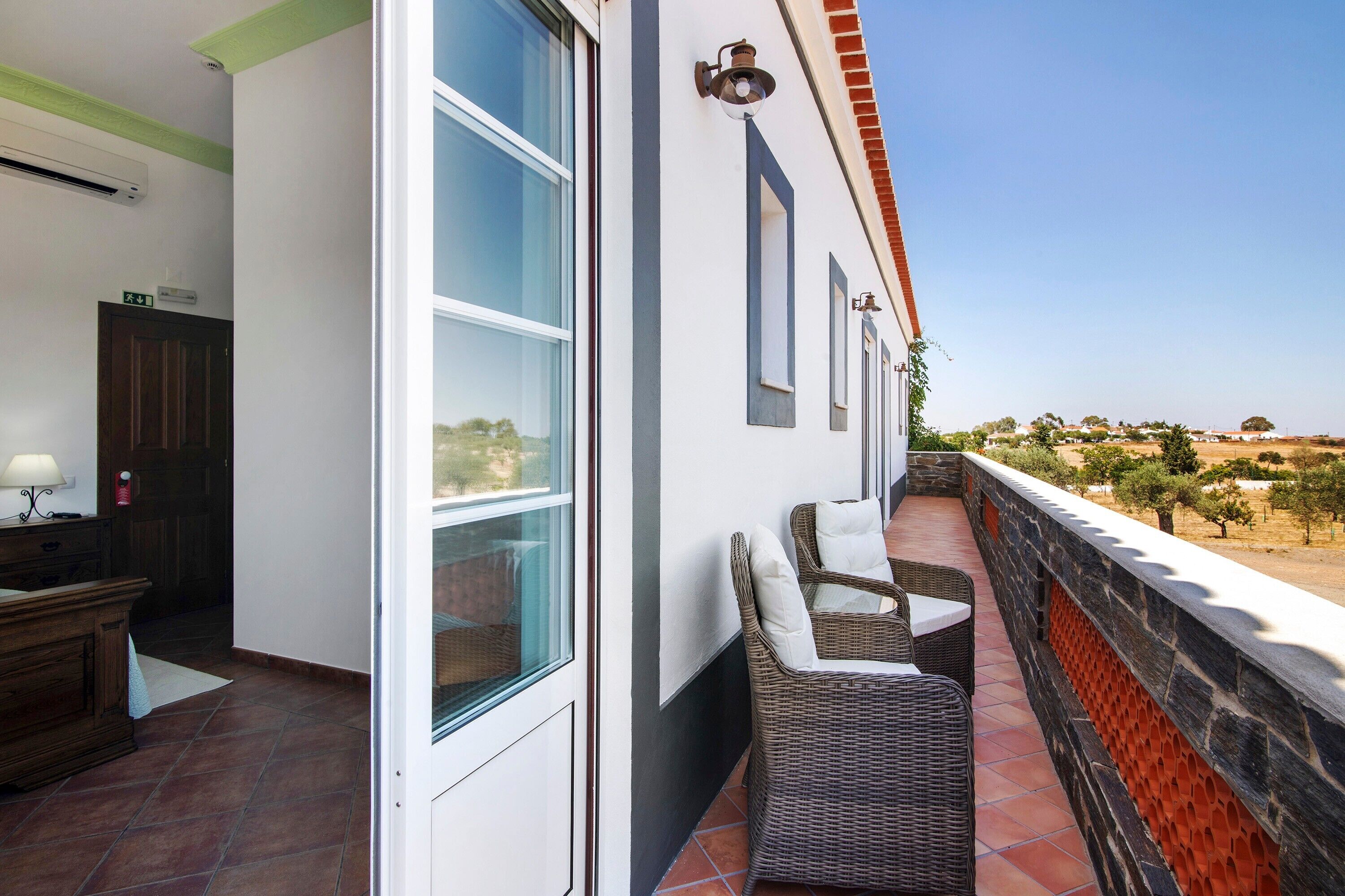 A balcony with wicker furniture, a door, and a view of the landscape.