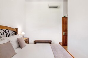 Une chambre à coucher avec un lit, une table de chevet, une lampe et un banc en bois.