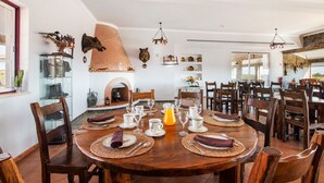 Un espace repas avec une grande table en bois, dressée pour un repas, entourée de chaises.