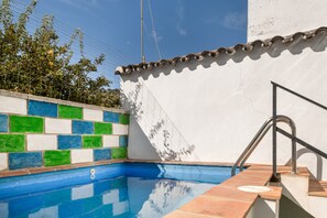 Piscina com parede e telhado revestidos em azulejo, e corrimão de metal.