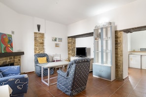 Una sala de estar con sofá, sillón, televisor y aparador.