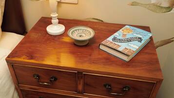 Een houten nachtkastje met een boek getiteld 'The Unbearable Lightness of Scones' en een witte lamp.