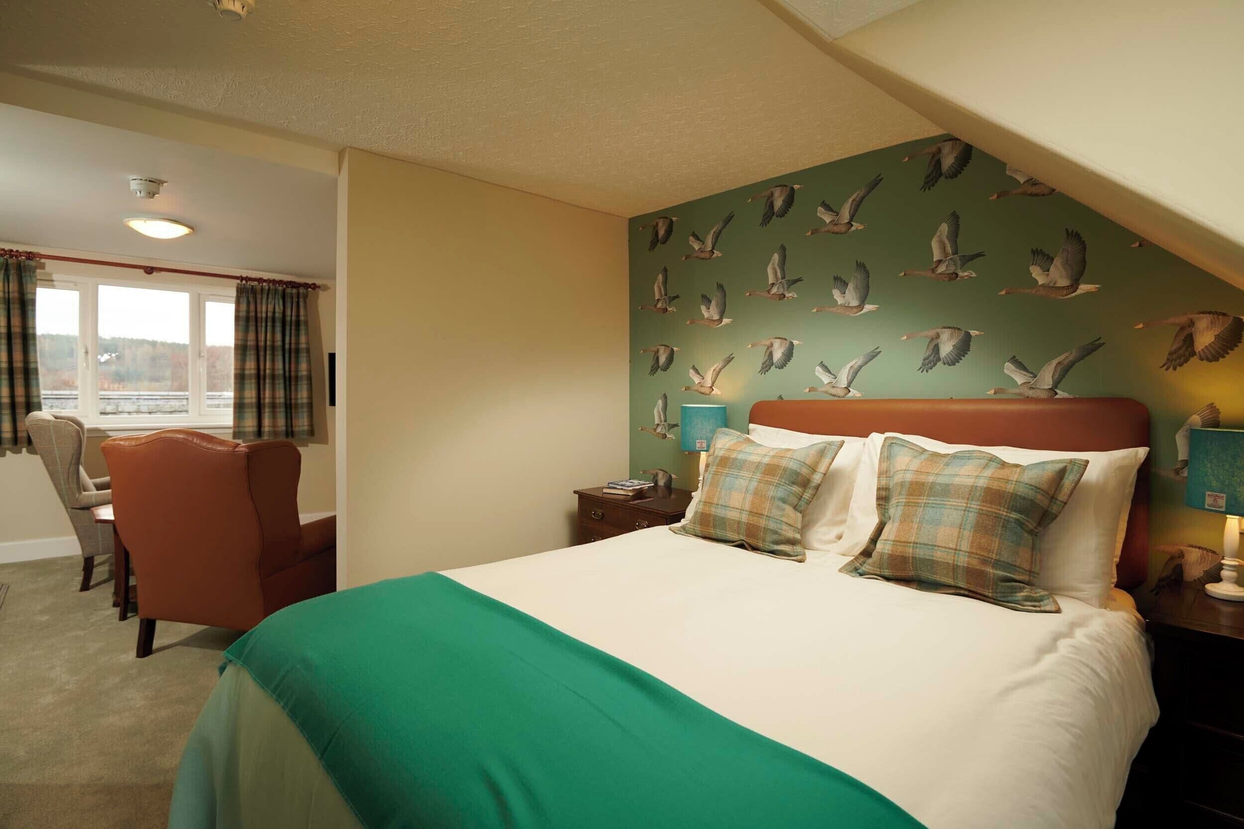 A hotel room with a large bed, a desk, and a view of the outdoors.