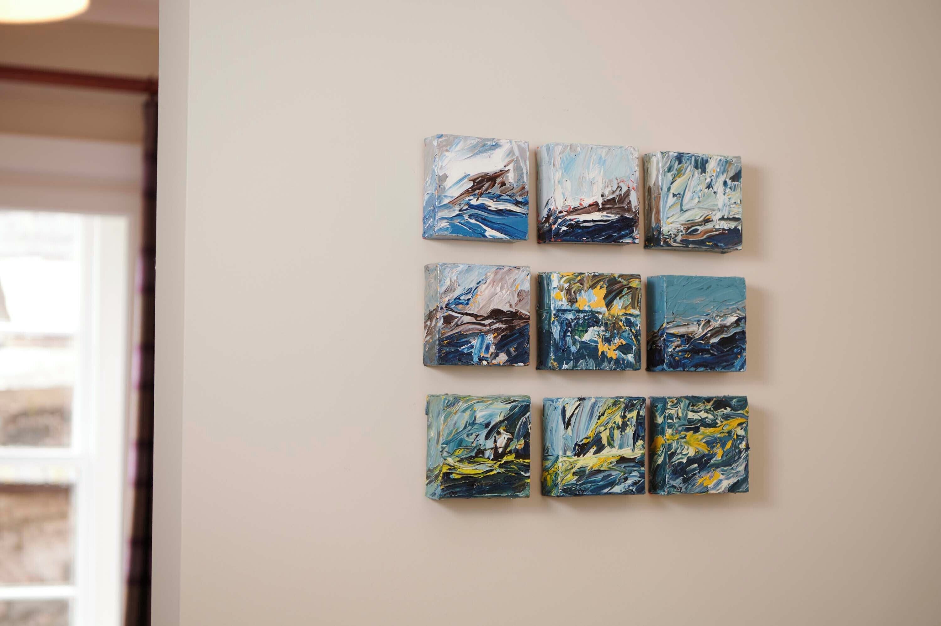 A series of abstract paintings on a wall.