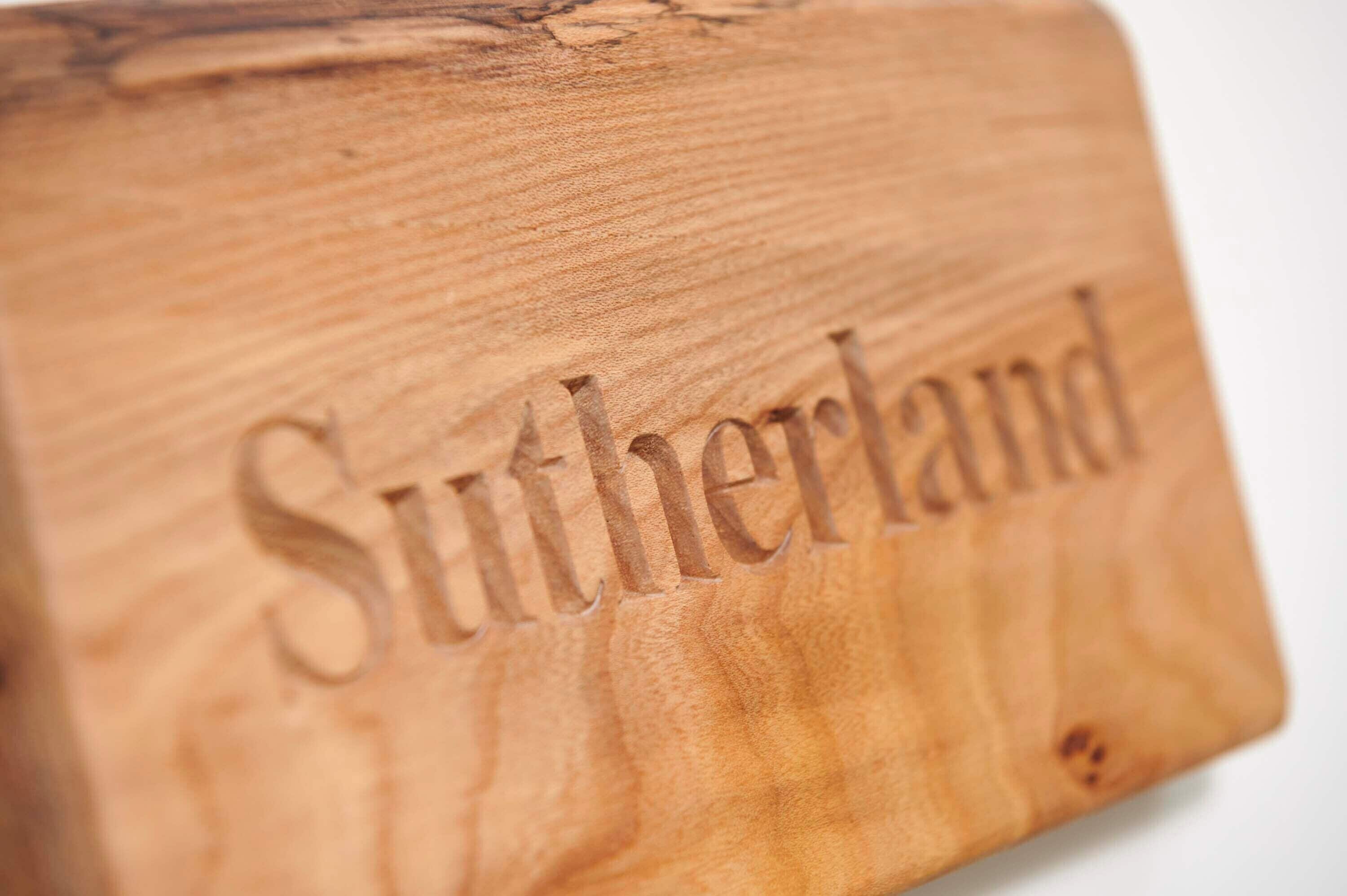 A wooden surface with the word "Sutherland" carved into it.