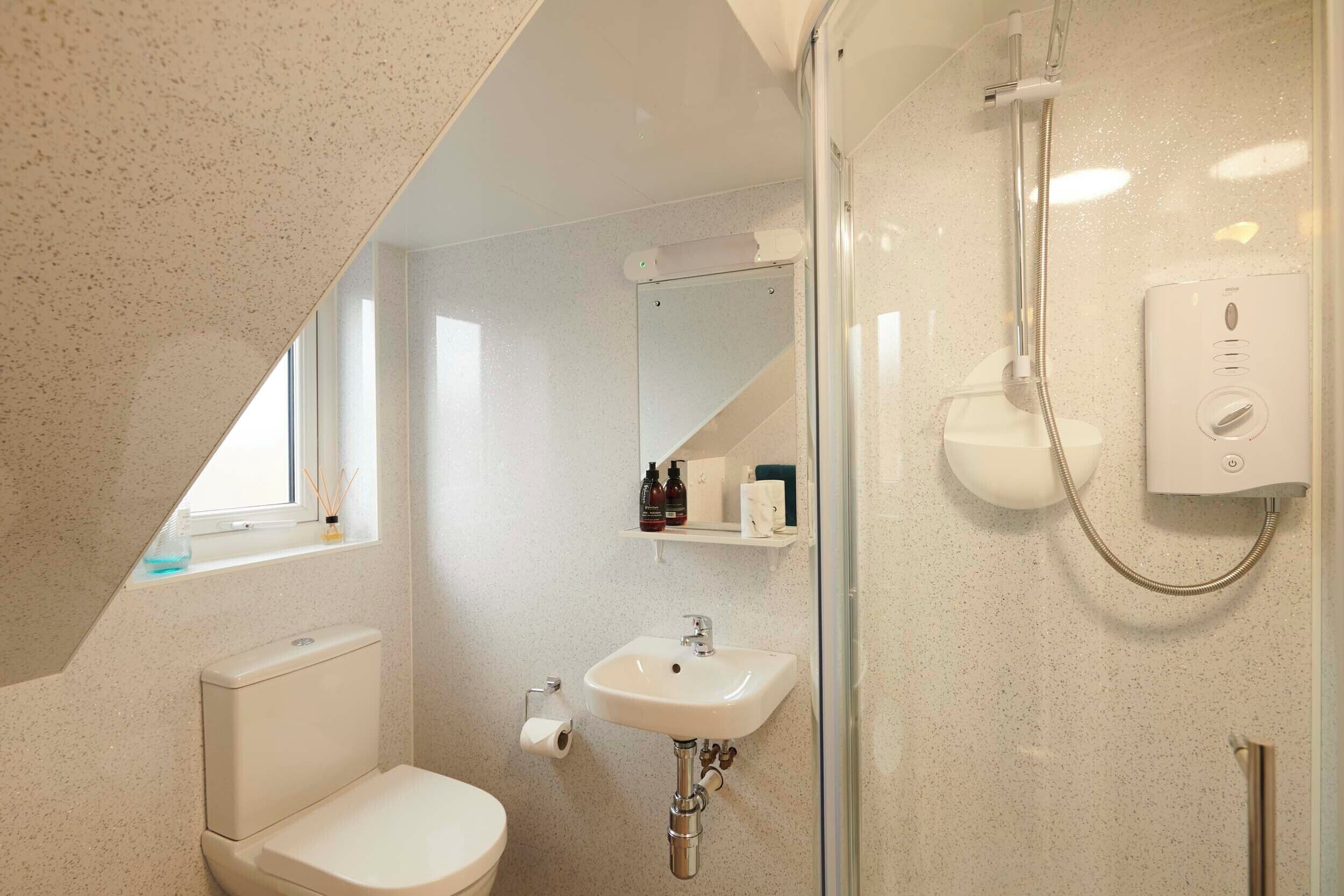 A bathroom with a toilet, sink, and shower.