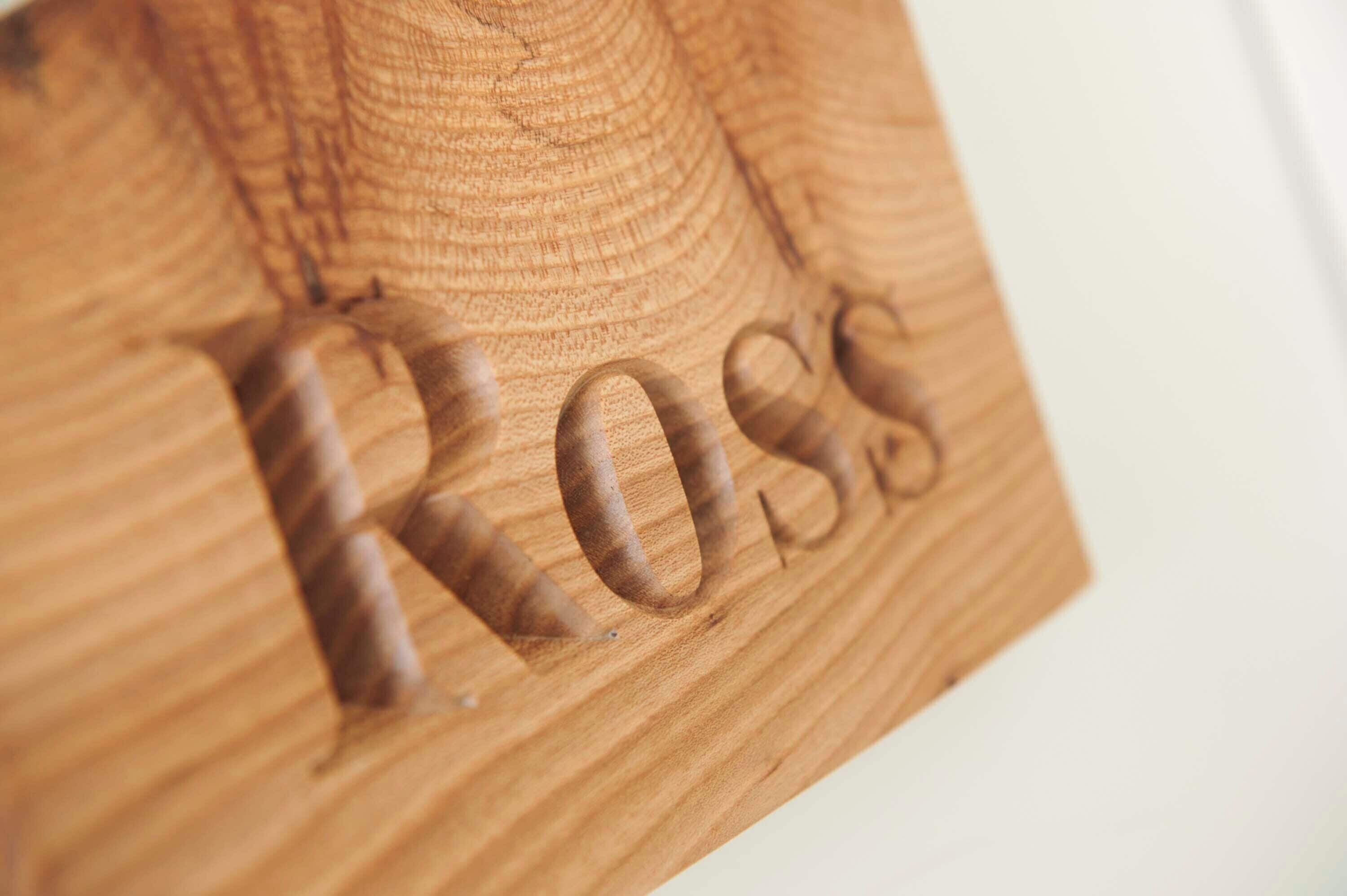 Eine Holzfläche mit dem eingravierten Wort "ROSS".