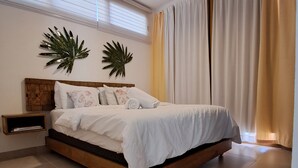 A bedroom with a wooden bed, a nightstand, two wall-mounted plants, a ceiling fan, and a large window with curtains.