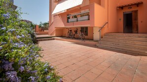 Ein Gebäude mit Balkon, Treppe und draußen abgestellten Fahrrädern.