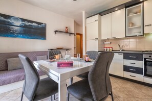 Una cucina moderna con mobili bianchi, un tavolo da pranzo con sedie e un quadro raffigurante un cielo notturno.