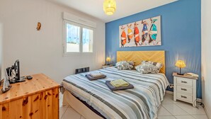Een slaapkamer met een bed, nachtkastjes, een bureau en een raam.