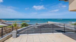 Een balkon met uitzicht op de oceaan, een hekwerk en een bloempot.