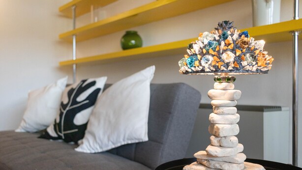 Un soggiorno moderno con un divano grigio, un albero di vetro decorativo e un tavolino nero.