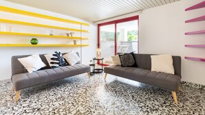 Un soggiorno moderno con due divani, un pavimento decorato e un mobile contenitore giallo brillante.