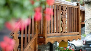 A wooden balcony railing with a carved sign, a stone wall, and a parked car. - Apartment 'Sotto' with Private Terrace and Wi-Fi (Morgex)