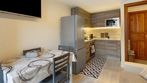 A compact kitchen with a refrigerator, microwave, oven, and wooden cabinets. - Apartment 'Sotto' with Private Terrace and Wi-Fi (Morgex)