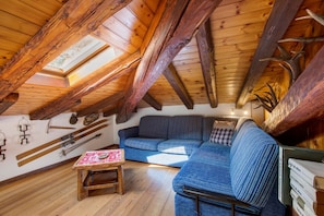 A loft-style room with exposed wooden beams, a blue sofa, and a small wooden table.