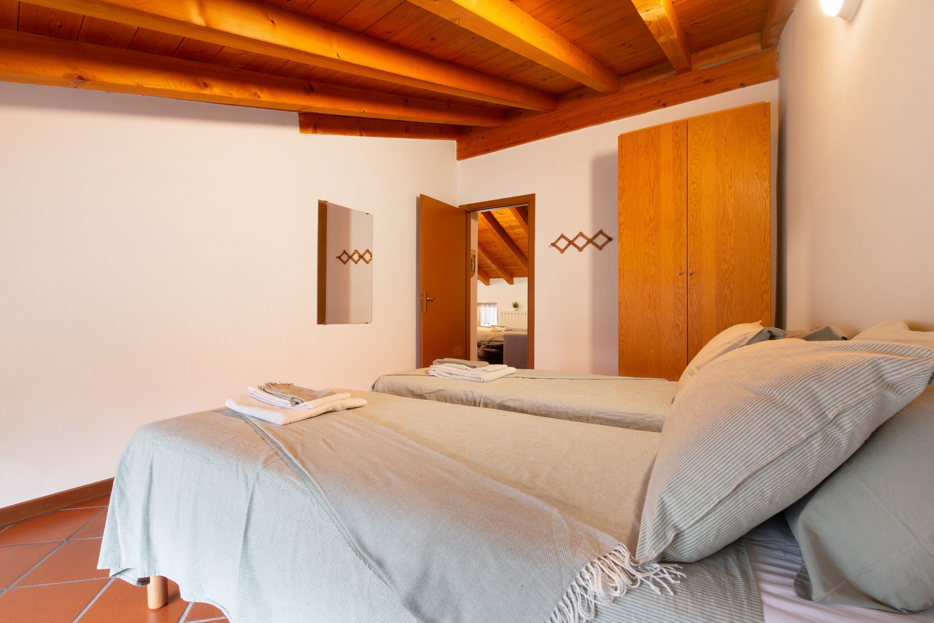 Un dormitorio con dos camas, vigas de madera, un espejo y un armario.