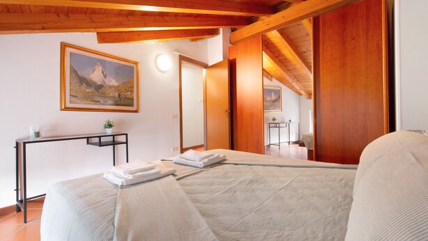 Une chambre à coucher avec un lit, un bureau, une chaise et un tableau accroché au mur.