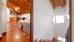 Une pièce avec un plafond en bois incliné, un lit, un bureau et une fenêtre.