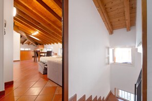 A room with a sloped wooden ceiling, a bed, a desk, and a window.