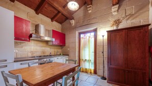 Una cocina con mesa de madera, sillas, estufa y armarios.