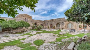 A courtyard with stone walls, a small garden area, and a building with arched windows. - Room 'Masseria Copertini - Gattini' with Wi-Fi and Air Conditioning (Vernole)