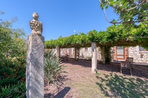 A stone building with a statue, outdoor seating, and a pergola covered with vines. - Room 'Masseria Copertini - Cervo' with Private Terrace, Wi-Fi and Air Conditioning (Vernole)