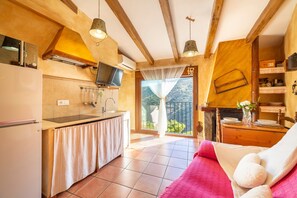 Una cocina con televisión, un lavamanos y una zona de comedor con mesa y sillas.