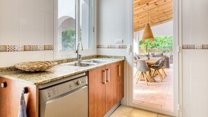Een keuken met een inbouwvaatwasser, een raam en uitzicht op een buiten eethoek.