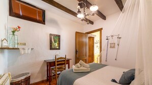 Ein Schlafzimmer mit Bett, Stuhl, Schreibtisch, Fenster und Tür.