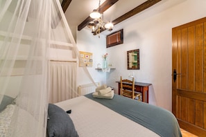 Un dormitorio con una cama, una puerta de madera, un escritorio y una silla.