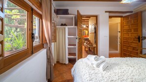 A bedroom with a bed, a window, a door, and a hallway leading to a bathroom. - Country House 'C´antonia Y Manuel' with Mountain View, Wi-Fi and Air Conditioning (Laroya)
