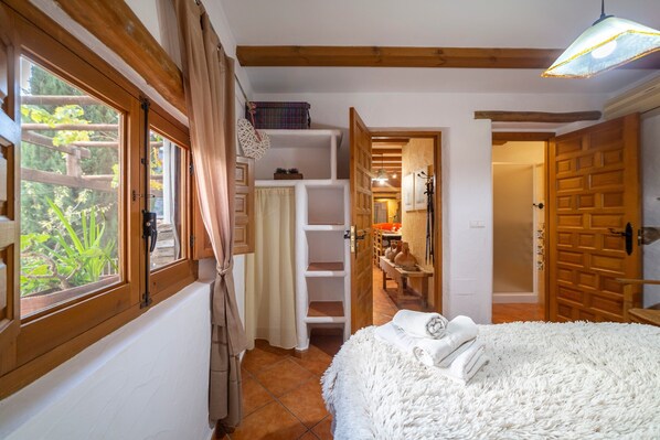 Un dormitorio con una cama, una ventana, una puerta y un pasillo que conduce a un baño.