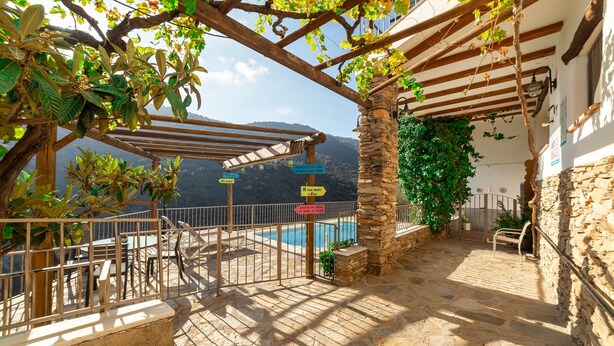 A stone patio with a pool, outdoor seating, and a pergola with climbing plants. - Country House 'C´antonia Y Manuel' with Mountain View, Wi-Fi and Air Conditioning (Laroya)