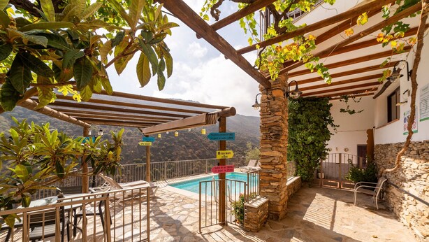 Une terrasse en pierre avec une piscine, un espace salon extérieur et une pergola.