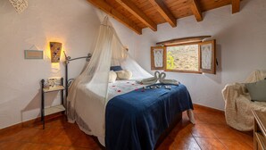 Une chambre à coucher avec un lit, une table de chevet, une fenêtre et un plafond en bois.