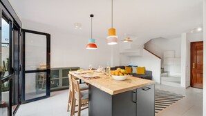A modern kitchen with a central island, pendant lights, and a view of the outdoors.