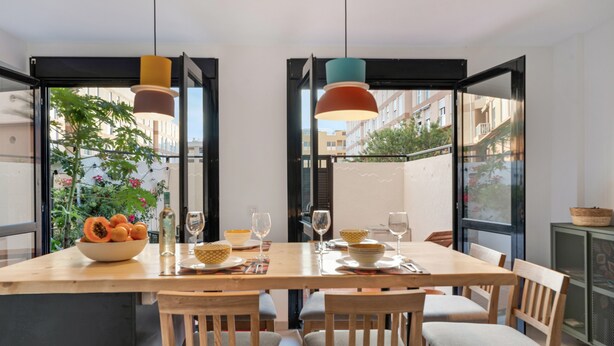 A dining area with a wooden table, chairs, and hanging pendant lights.