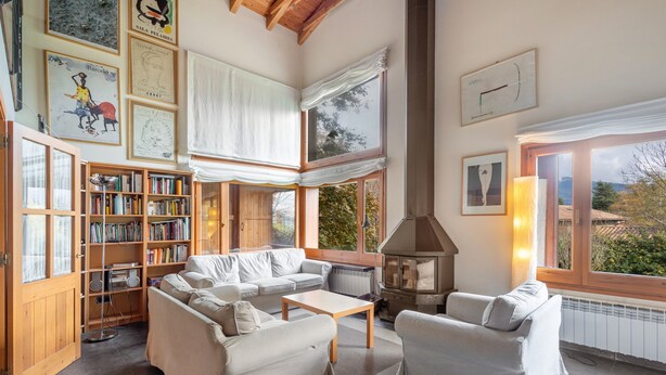 Un salon chaleureux avec une cheminée, une bibliothèque et une grande fenêtre donnant sur un beau paysage.
