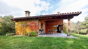 Une maison avec un patio couvert, une cheminée et un barbecue à l’extérieur.