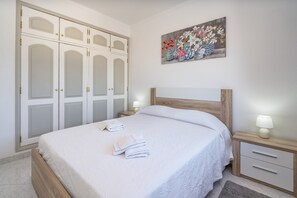 Une chambre à coucher comprenant un lit, une table de chevet, une tête de lit en bois, une armoire et un tableau accroché au mur.