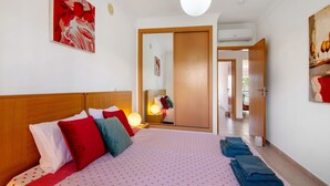 A hotel room with a bed, pillows, a bedside lamp, a wardrobe, and a mirror.