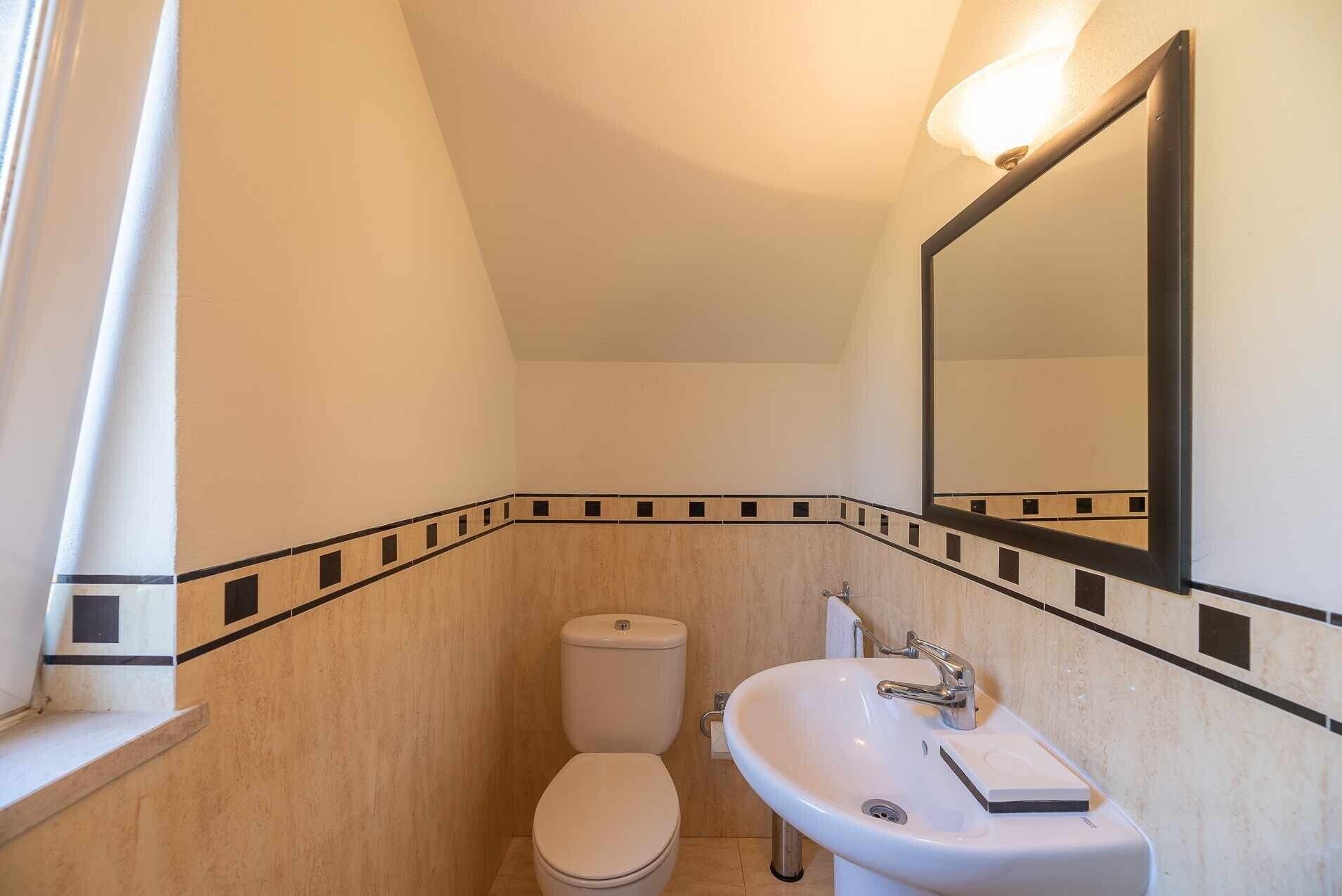 A small bathroom with a toilet, sink, and mirror.